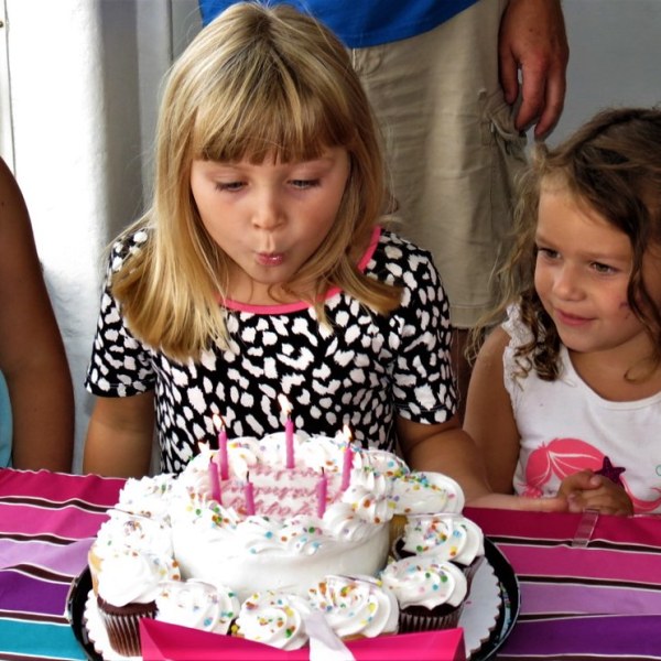 a little girl sitting at a table with a birthday cake