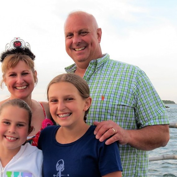 a little girl standing next to a body of water posing for the camera