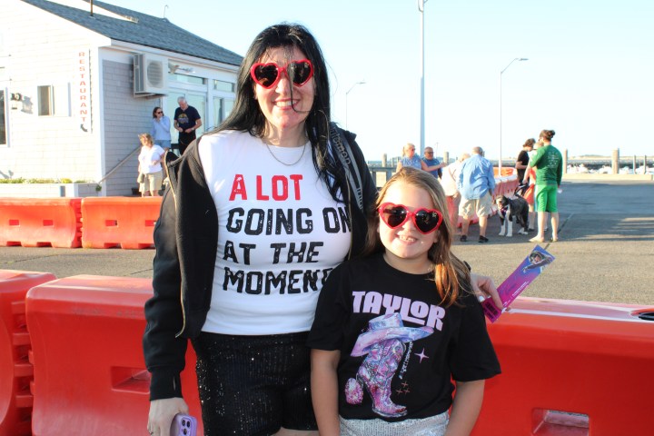 Two people wearing heart-shaped sunglasses, standing outdoors, in casual attire with graphic tees.