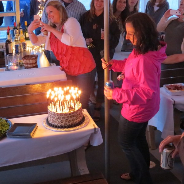 a group of people sitting at a table with a birthday cake