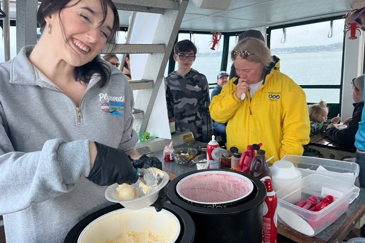 Woman smiling while scooping ice cream on a boat with others around.
