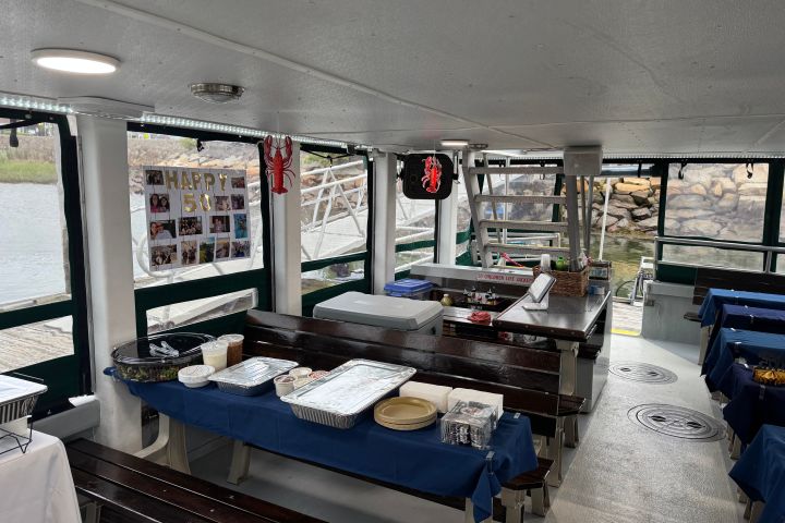 Inside a decorated boat with tables, food trays, and a 'Happy 50th' poster.