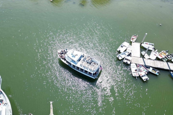 Aerial view of a large boat near a dock with several smaller boats floating around.