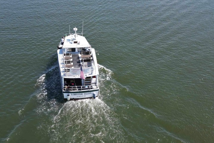 Boat with American flag sailing on water, viewed from above.